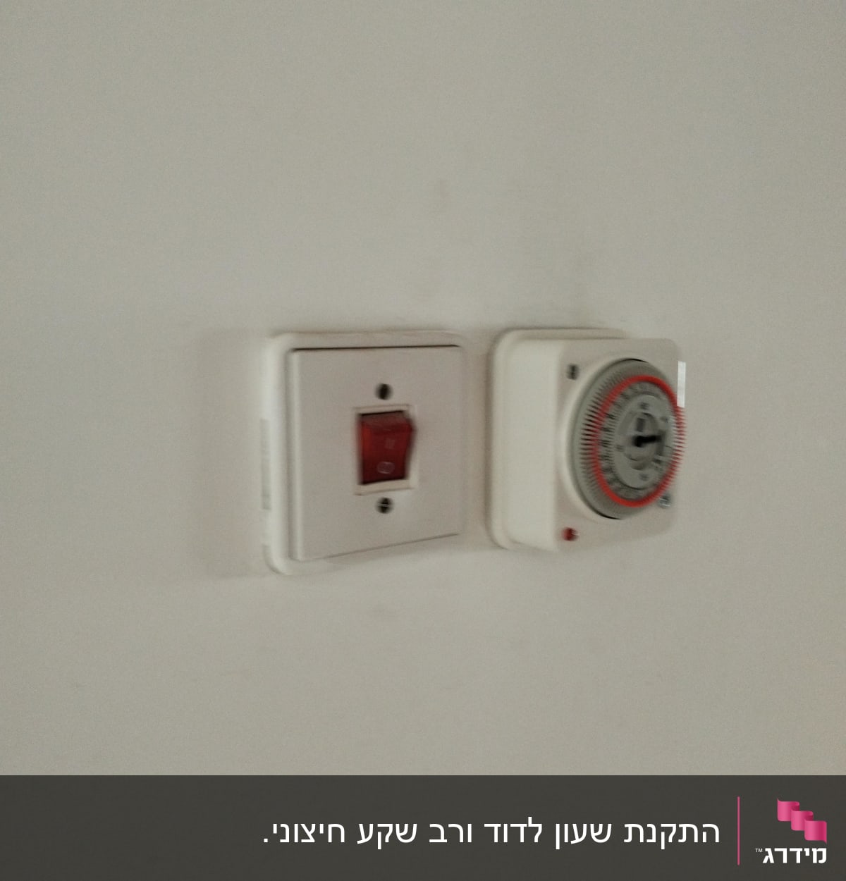 שקע חשמלי עם מתג אדום וטיימר על קיר לבן